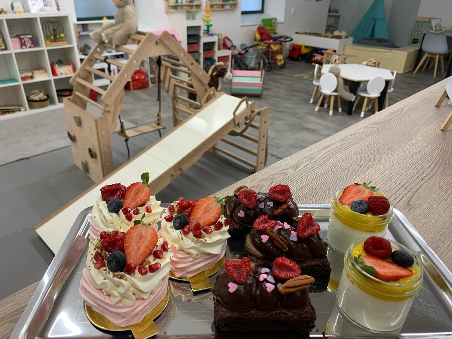 Talíř domácích zákusků s ovocem před dřevěnou prolézačkou